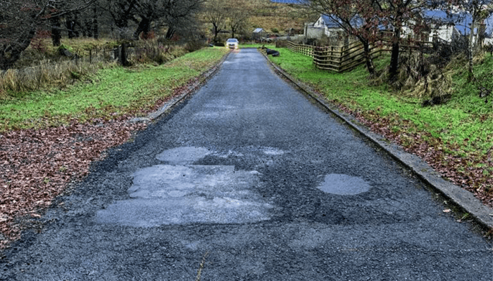 Weathered private roadway in Scotland marked out for repairwork