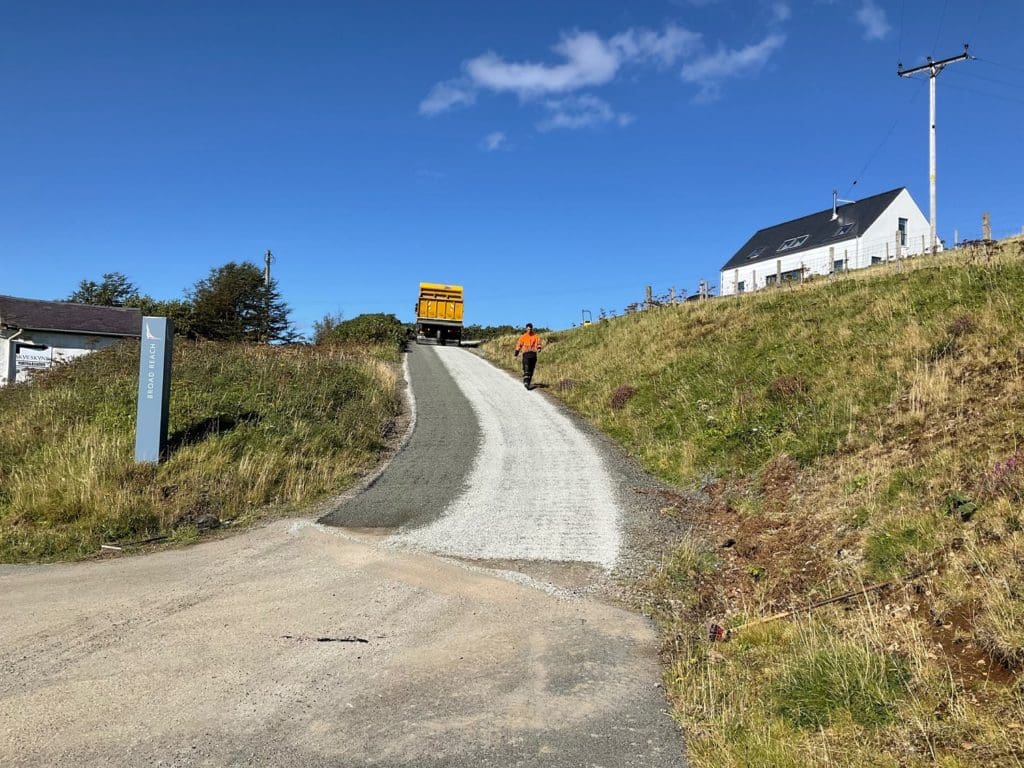 Tipper lorry laying surface dressing to a private road in Highlands 